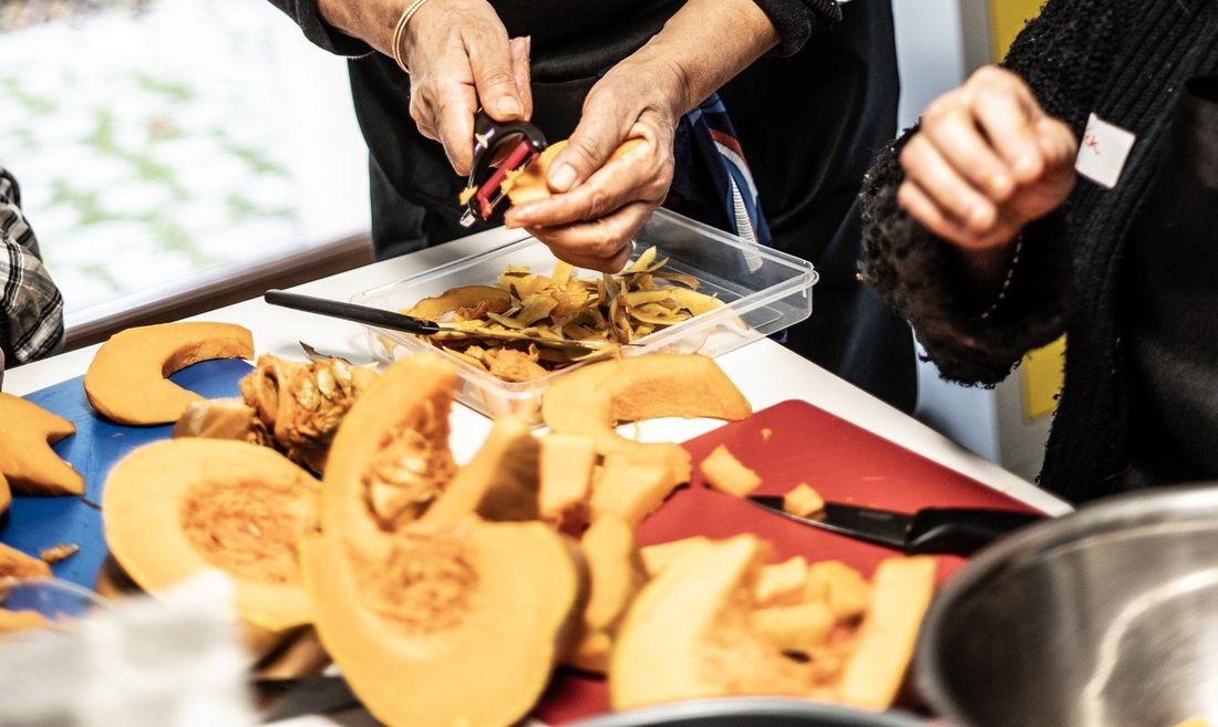 Mains de participantes préparant des courges de saison lors d'un atelier de cuisine